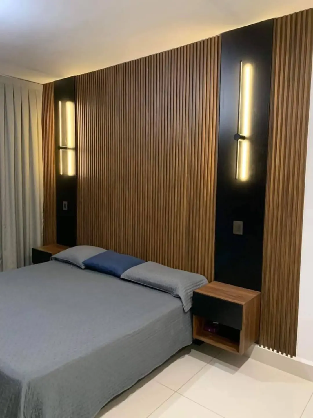 Quarto com cabeceira ripada e iluminação vertical
